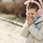 child blowing her nose with winter clothes