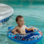 toddler smiling in an innertube floatie in a swimming pool