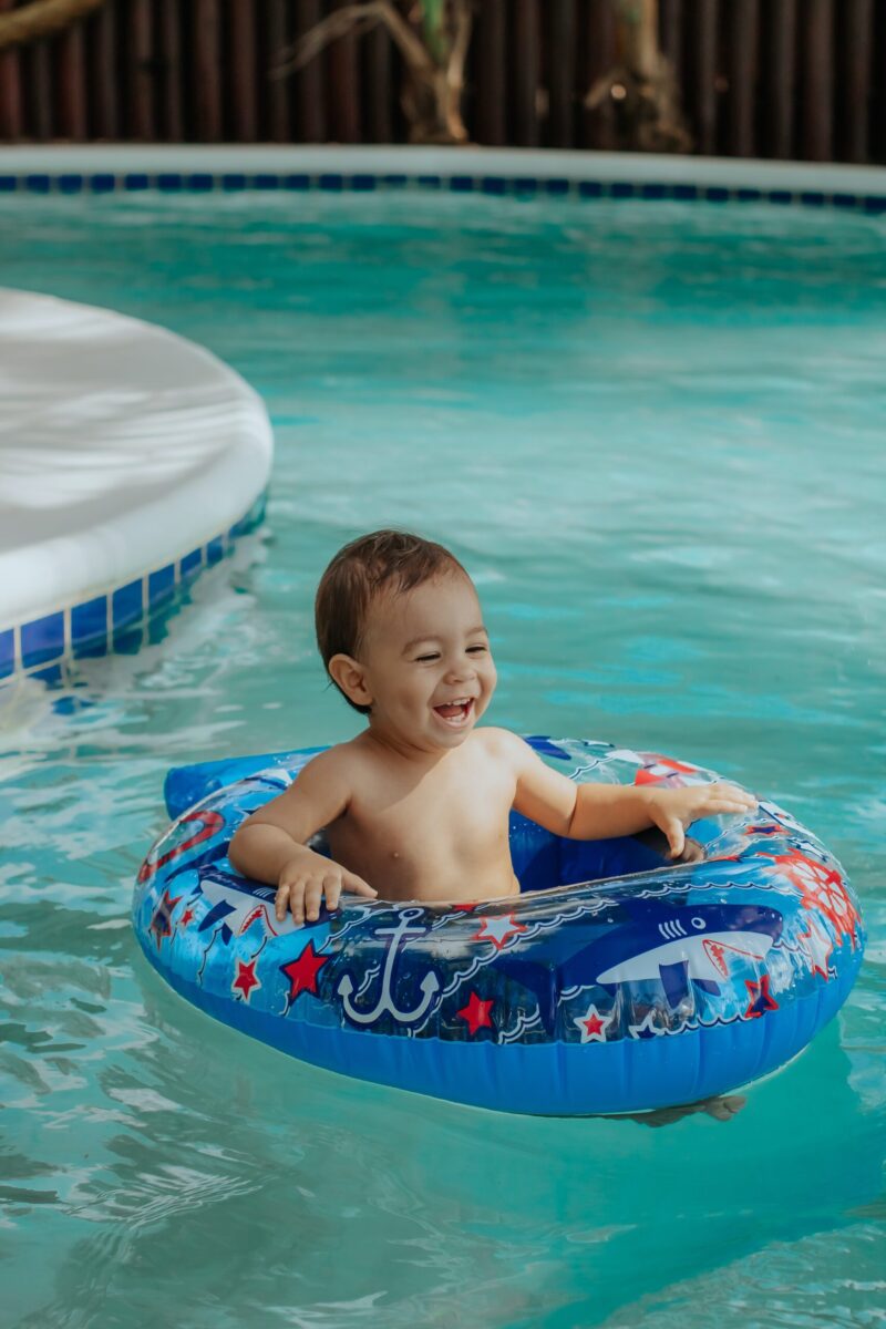 toddler smiling in an innertube floatie in a swimming pool